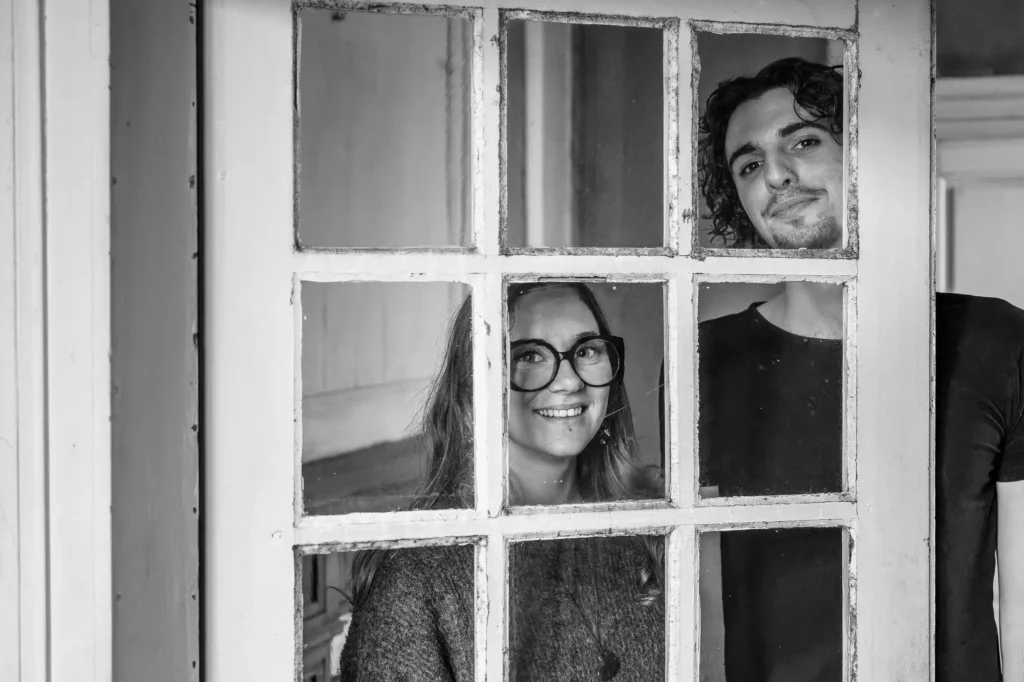 Photo de couple derrière une porte vitrée.